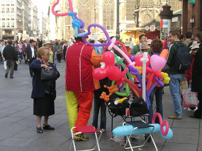 A man on the street making shapes with balloons